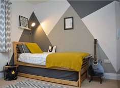 a bedroom with a bed, guitar and pictures on the wall above it is decorated in yellow and gray colors