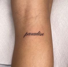 a woman's arm with the word paradise tattooed on her left side ribcage