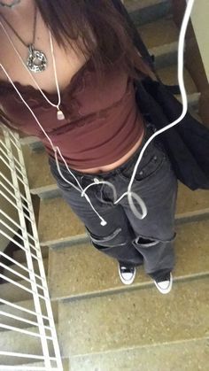 a woman is standing on the stairs with headphones in her ears and looking down