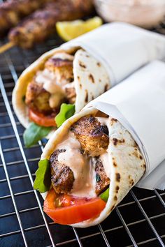 there are two wraps with meat and vegetables on them, sitting on a wire rack