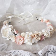 a white and pink flower crown on top of a lace doily