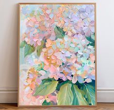 a painting with flowers on it in a frame next to a wall and hardwood floor