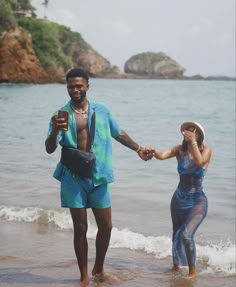 a man and woman holding hands on the beach