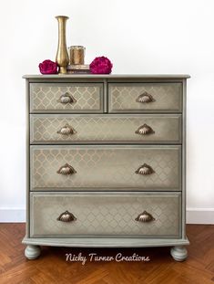 an old dresser has been painted with metallic paint and flowers on the top drawer, along with a gold vase