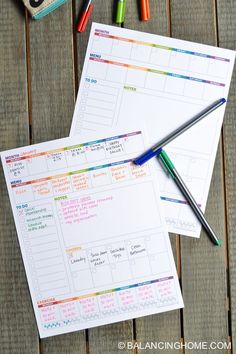 two sheets of paper sitting on top of a wooden table next to markers and pencils