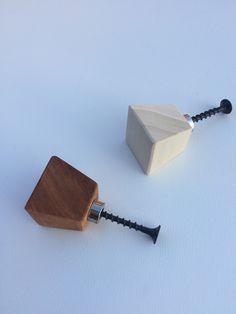 two small wooden objects sitting next to each other on a white surface with black handles