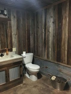 a bathroom with wood paneling and a toilet next to a sink in the corner