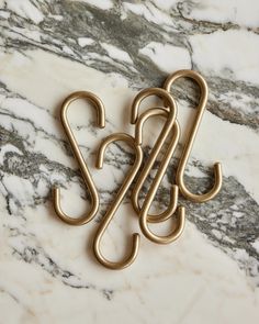 two metal hooks on top of a marble counter with the letter s spelled in it