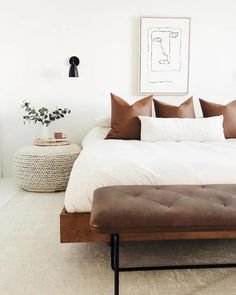 a bed with white sheets and brown pillows