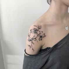 a woman's shoulder with flowers on it and the words tattoos written below her arm