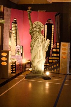 the statue of liberty is lit up in front of a red wall with city lights