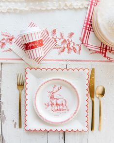 a christmas place setting with red and white napkins, silverware, and gold utensils