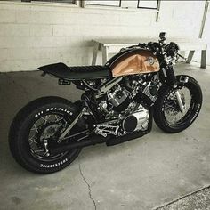 a black and white photo of a motorcycle parked in front of a building with a bench