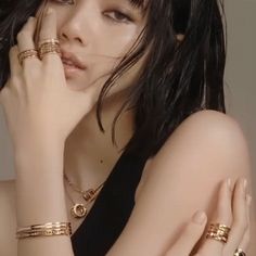 a woman with long black hair wearing gold rings and bracelets on her arm, posing for the camera