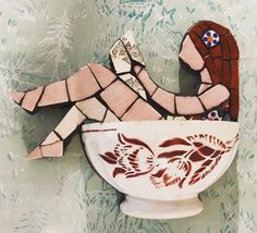 there is a bowl with a mosaic design on the side that has a woman sitting in it