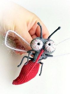 a tiny crocheted insect is being held by a person's hand,