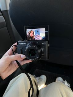 a person holding up a camera in the back seat of a car while taking a photo