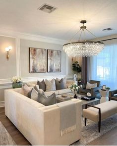 a living room filled with furniture and a chandelier hanging over the top of it