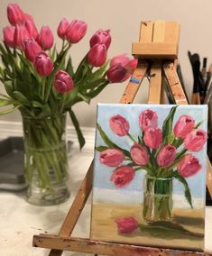 pink tulips are in a vase on an easel