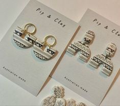 two pairs of earrings sitting next to each other on top of a white card with black and white designs