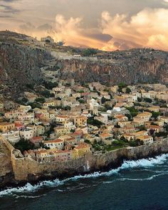 an aerial view of a small village on the edge of a cliff by the ocean