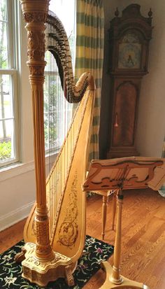 a large wooden harp sitting on top of a hard wood floor next to a window