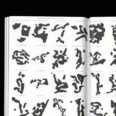 an open book with black and white ink drawings on it's pages, including letters and numbers