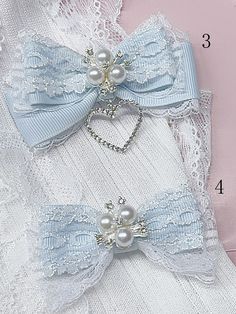 two pieces of white lace with bows and pearls on them are laying next to each other