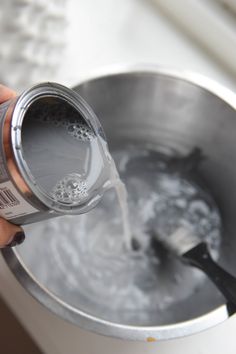 a person pouring water into a metal pot