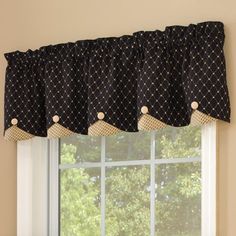 a window with a black and white valance hanging from it's side next to a potted plant