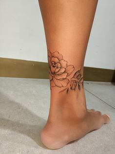 a woman's foot with a rose tattoo on the side of her leg,