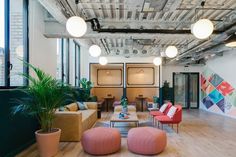 an office with couches, chairs and potted plants in the middle of the room