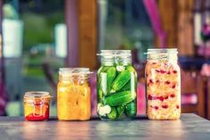 four jars filled with pickles and other vegetables