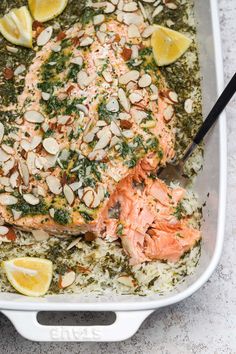 salmon and rice in a white dish with lemons, almonds and parsley