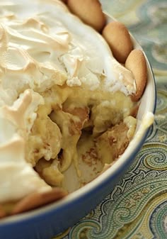 there is a pie with white frosting and nuts in the bowl on the table