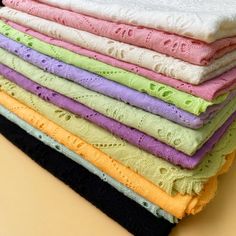 a stack of folded towels sitting on top of a table next to each other in different colors