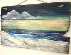 a wooden sign hanging on the side of a wall with an ocean scene painted on it