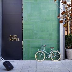 a white bike parked next to a green building with a sign that says alex hotel