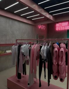 clothes are hanging on racks in a clothing store with neon signs above them and pink lighting