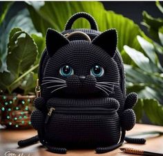 a black cat purse sitting on top of a table next to a potted plant