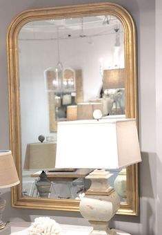 a large mirror sitting on top of a white table next to a lamp and lampshade