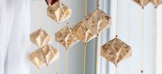 a close up of an origami mobile hanging from a curtain with beads attached to it