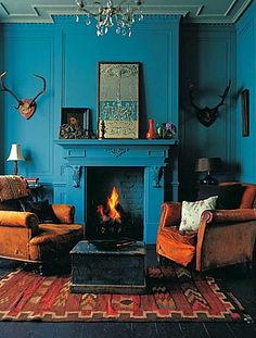 a living room filled with furniture and a fire place in front of a blue wall