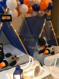 two beds with stuffed animals on them and balloons in the air behind them at a children's birthday party