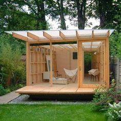 a small wooden structure in the middle of a yard with grass and trees around it