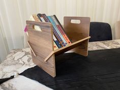 a wooden book stand on top of a table with books in it and an umbrella nearby