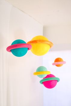 three colorful balls hanging from the ceiling in a room with white walls and flooring