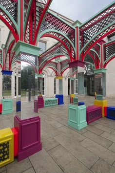 colorful benches are lined up in the middle of an open area with arches and windows