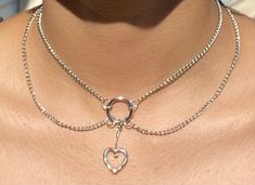 Layered chain, choker-style necklace with heart charm center! Can be extended up to one inch. Model is wearing a 13 in. necklace. Metal Heart Choker With Heart Charm, Heart Charm Metal Choker, Metal Heart Charm Choker, Silver Heart Chain Choker, Silver Heart-shaped Chain Choker, Trendy Metal Choker With Heart Pendant, Trendy Silver Heart-shaped Choker, Heart Charm Metal Choker With Heart Pendant, Metal Heart Charm Choker With Heart Pendant