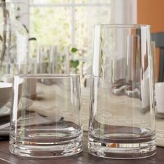 two clear glasses sitting on top of a wooden table